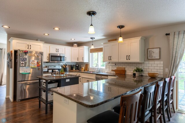 4408 Riverwood Dr N, Fargo, ND 58102 - kitchen with appliances with stainless steel finishes, a sink, a peninsula, dark wood-type flooring, and white cabinets