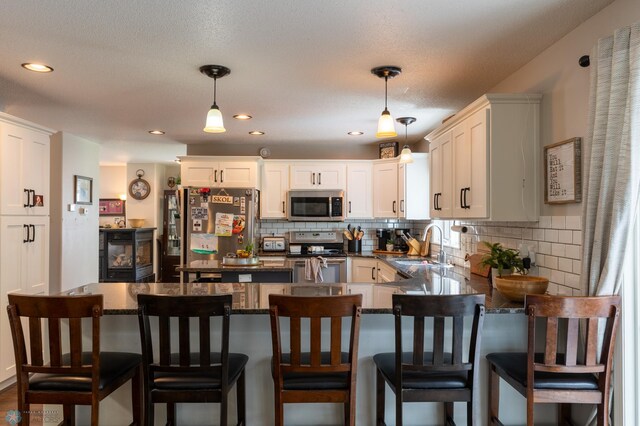 4408 Riverwood Dr N, Fargo, ND 58102 - kitchen featuring appliances with stainless steel finishes, a sink, dark countertops, decorative backsplash, and decorative light fixtures