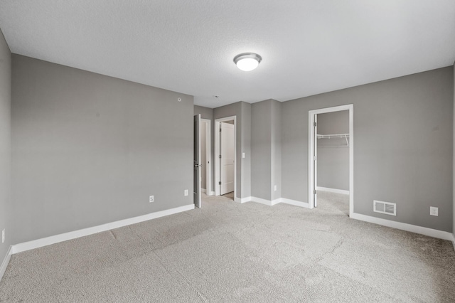 5040 93rd Ln N, Brooklyn Park, MN 55443 - unfurnished bedroom with baseboards, carpet, a walk in closet, a closet, and a textured ceiling