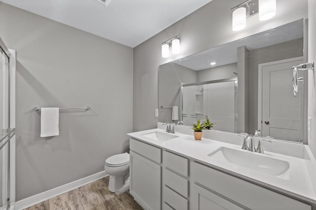 5040 93rd Ln N, Brooklyn Park, MN 55443 - bathroom with a stall shower, toilet, wood finished floors, double vanity, and baseboards