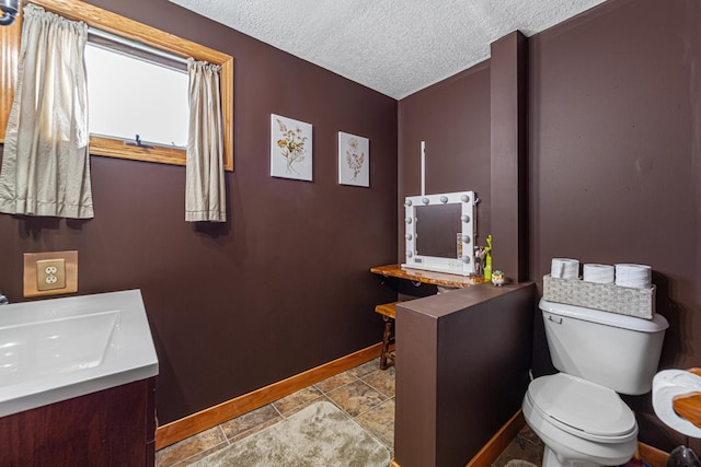 18023 Roberds Lake Blvd, Faribault, MN 55021 - half bath featuring baseboards, toilet, vanity, a textured ceiling, and stone finish flooring