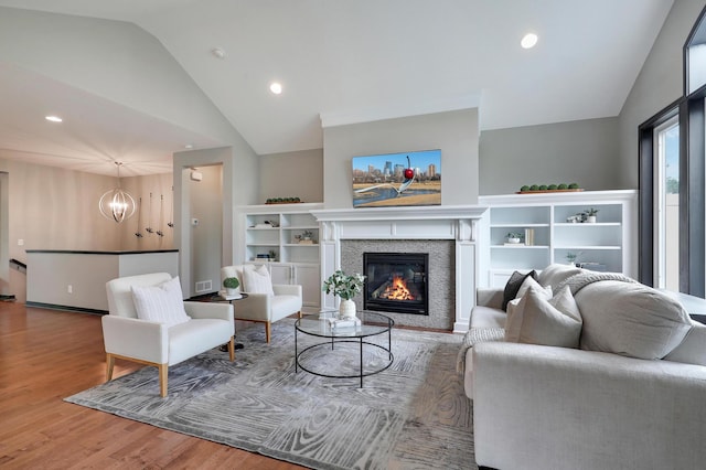 2524 Sandstone Ln, Orono, MN 55356 - living room featuring lofted ceiling, a chandelier, a glass covered fireplace, wood finished floors, and recessed lighting