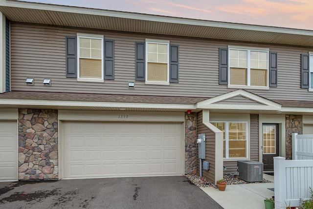 1212 Lower 143rd St E, Rosemount, MN 55068 - view of property with stone siding, central AC, a garage, asphalt driveway, and a shingled roof