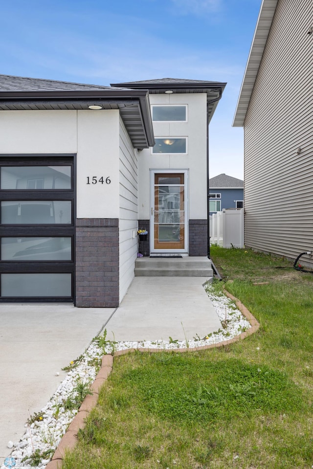 1546 68th Ave S, Fargo, ND 58104 - property entrance featuring brick siding, driveway, and a garage