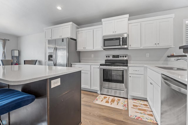 1546 68th Ave S, Fargo, ND 58104 - kitchen featuring appliances with stainless steel finishes, a sink, a kitchen bar, light wood-style flooring, and white cabinetry