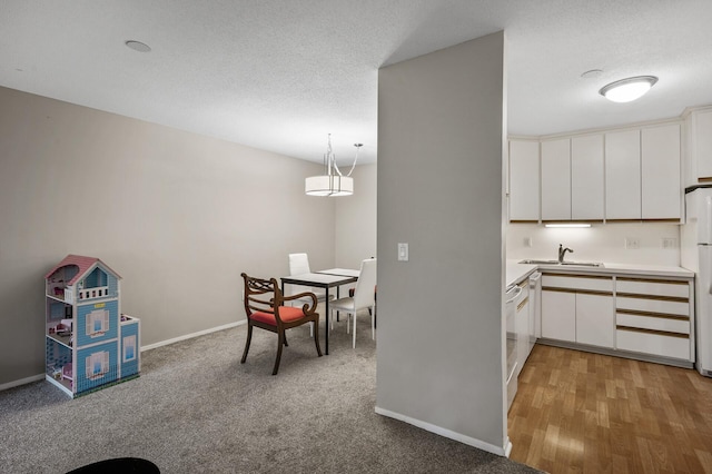 7510 Cahill Rd Unit 211B, Edina, MN 55439 - kitchen featuring light countertops, white cabinetry, freestanding refrigerator, hanging light fixtures, and a textured ceiling