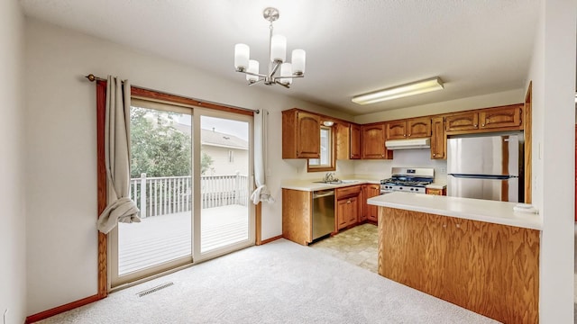 2209 18th Ave SE, Rochester, MN 55904 - kitchen featuring appliances with stainless steel finishes, under cabinet range hood, light countertops, brown cabinets, and a chandelier