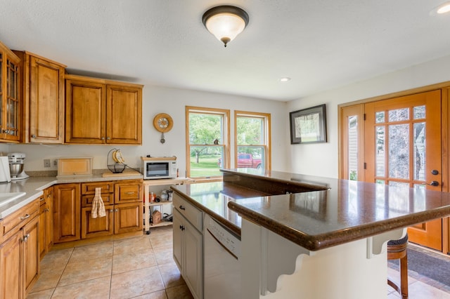 N8355 330th St, Gilman Twp, WI 54767 - kitchen with white microwave, brown cabinetry, a kitchen bar, recessed lighting, and light tile patterned floors