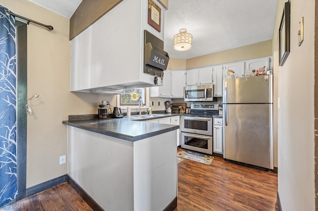 226 12th Ave W, West Fargo, ND 58078 - kitchen featuring stainless steel appliances, a sink, a peninsula, a textured ceiling, and dark countertops