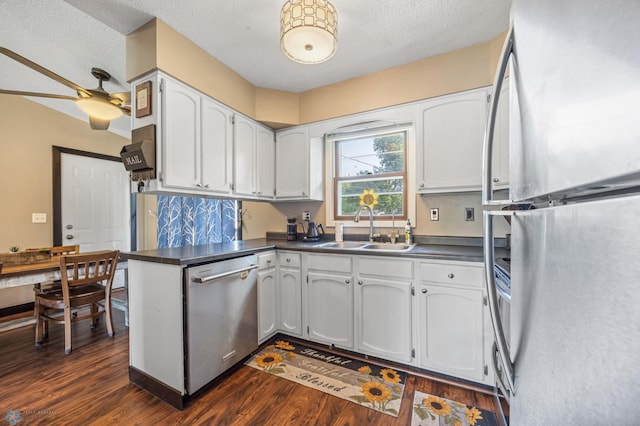 226 12th Ave W, West Fargo, ND 58078 - kitchen with appliances with stainless steel finishes, a sink, dark countertops, dark wood finished floors, and white cabinetry