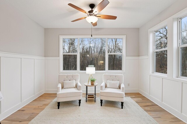 1843 Campfire Dr E, Waconia, MN 55387 - living area featuring a decorative wall, light wood finished floors, wainscoting, and ceiling fan