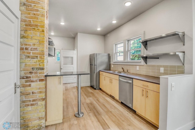 1036 12th St N, Fargo, ND 58102 - kitchen featuring stainless steel appliances, a sink, light brown cabinetry, light wood-style flooring, and dark countertops