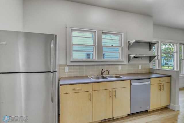1036 12th St N, Fargo, ND 58102 - kitchen featuring appliances with stainless steel finishes, light brown cabinetry, a sink, light wood-style flooring, and decorative backsplash