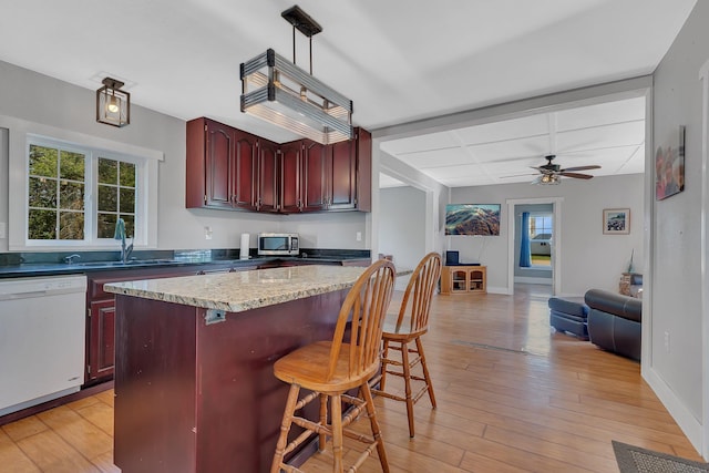 37454 605th Ave, Bluffton Twp, MN 56518 - kitchen featuring white dishwasher, reddish brown cabinets, a sink, stainless steel microwave, and a center island