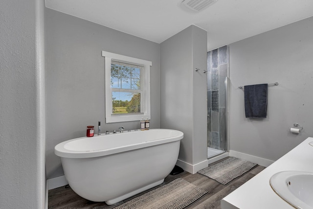 37454 605th Ave, Bluffton Twp, MN 56518 - full bathroom featuring a stall shower, a freestanding bath, wood finished floors, and baseboards