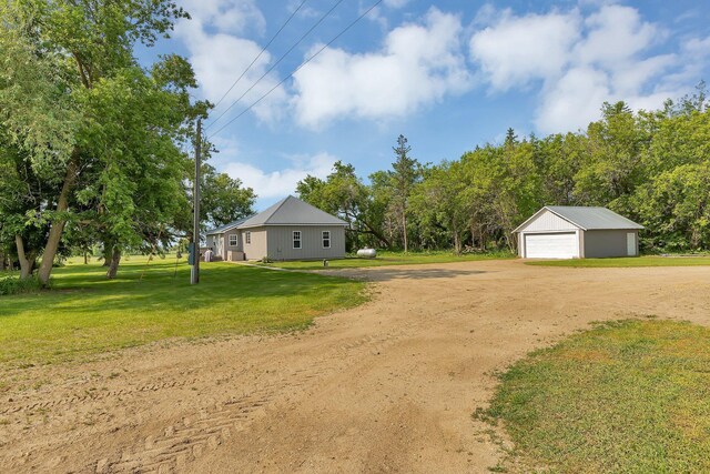 37454 605th Ave, Bluffton Twp, MN 56518 - view of green lawn featuring a garage, dirt driveway, and an outdoor structure
