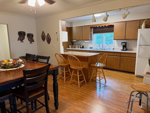 30055 Shore Dr, Pengilly, MN 55775 - kitchen with freestanding refrigerator, brown cabinets, a kitchen breakfast bar, light countertops, and a ceiling fan