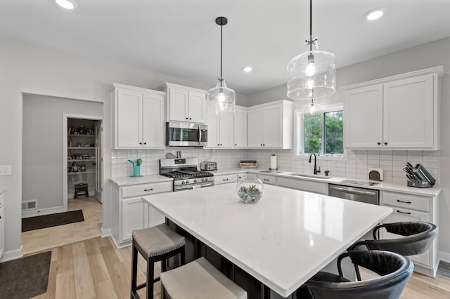 5945 178th St W, Lakeville, MN 55044 - kitchen with stainless steel appliances, a sink, light wood-type flooring, a breakfast bar area, and recessed lighting