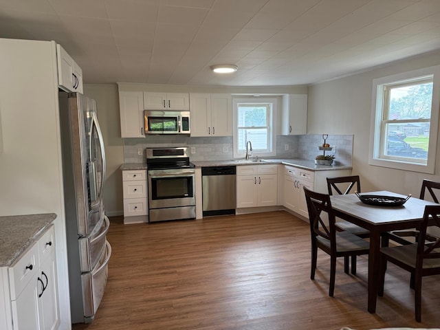 604 10th Ave, Grand Rapids, MN 55744 - kitchen with stainless steel appliances, backsplash, dark wood finished floors, white cabinets, and light stone counters
