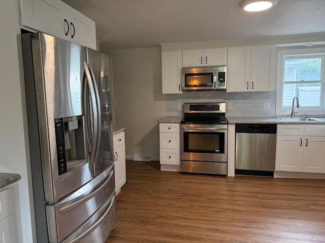 604 10th Ave, Grand Rapids, MN 55744 - kitchen featuring stainless steel appliances, backsplash, dark wood-style flooring, white cabinetry, and ornamental molding