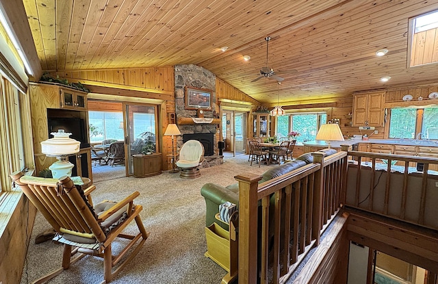 27315 Stark Lake Rd, Aitkin, MN 56431 - living room featuring lofted ceiling, wooden ceiling, wood walls, carpet floors, and a stone fireplace
