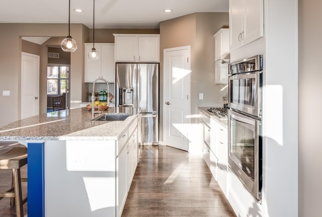 10329 Kentucky Ave N, Brooklyn Park, MN 55445 - kitchen featuring stainless steel appliances, dark wood-style flooring, a breakfast bar, a center island with sink, and white cabinets