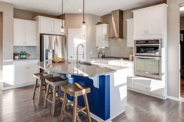 10329 Kentucky Ave N, Brooklyn Park, MN 55445 - kitchen featuring wall chimney range hood, stainless steel appliances, decorative backsplash, dark wood-style floors, and a center island with sink