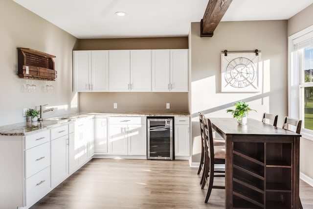 10329 Kentucky Ave N, Brooklyn Park, MN 55445 - kitchen featuring beverage cooler, light wood-style flooring, light stone countertops, white cabinetry, and recessed lighting