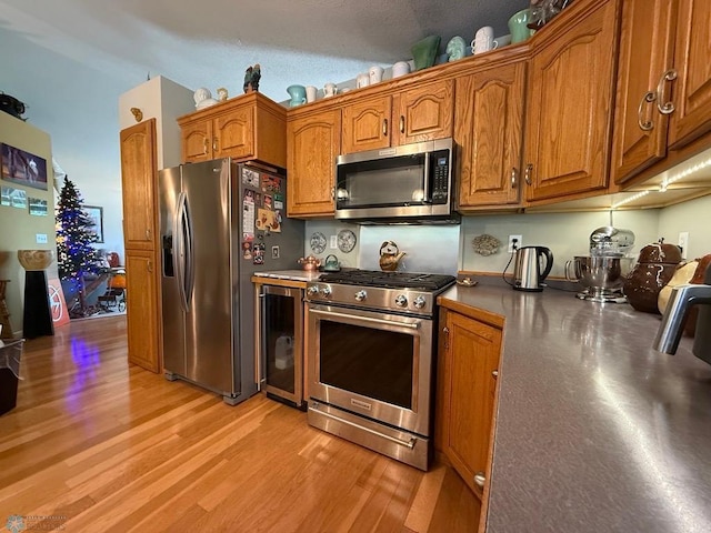 521 Kroshus Dr, Dilworth, MN 56529 - kitchen featuring stainless steel appliances, brown cabinets, beverage cooler, and light wood-style floors