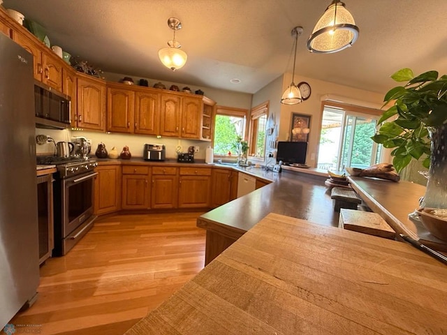 521 Kroshus Dr, Dilworth, MN 56529 - kitchen featuring appliances with stainless steel finishes, light wood-style floors, brown cabinetry, pendant lighting, and open shelves