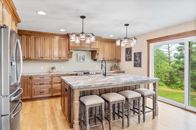 3546 230th St E, Prior Lake, MN 55372 - kitchen featuring stainless steel appliances, light wood-style flooring, a kitchen bar, light stone counters, and a kitchen island with sink