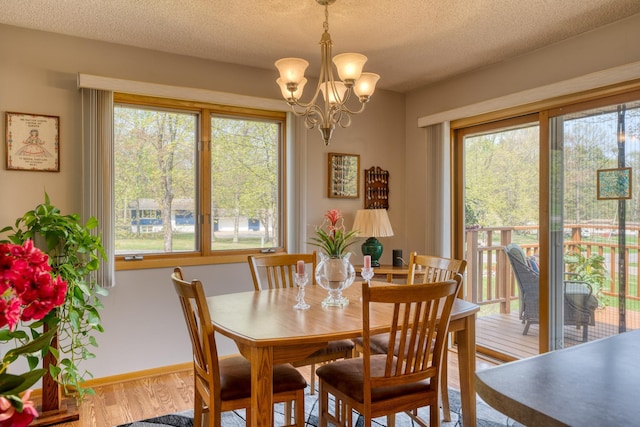 33240 Gary Dr, Grand Rapids, MN 55744 - dining area with wood finished floors, a chandelier, a textured ceiling, and baseboards