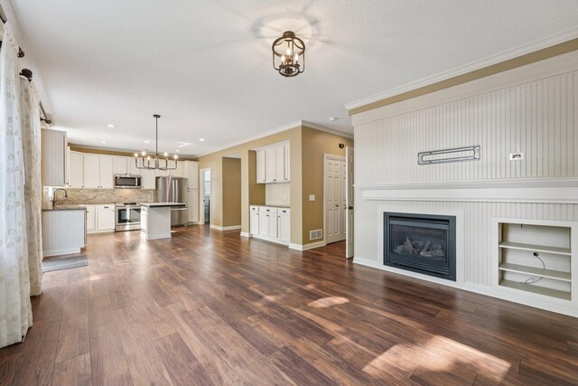 1741 Prescott Ln, Chaska, MN 55318 - unfurnished living room with a chandelier, crown molding, baseboards, dark wood-type flooring, and a sink