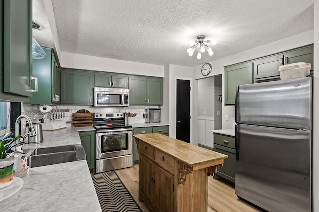 3717 80th Ave N, Brooklyn Park, MN 55443 - kitchen featuring stainless steel appliances, green cabinets, a sink, light wood-style flooring, and tasteful backsplash