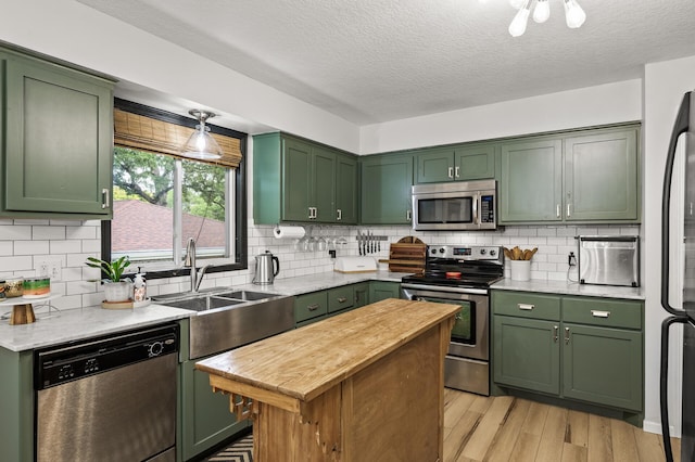 3717 80th Ave N, Brooklyn Park, MN 55443 - kitchen featuring green cabinets, appliances with stainless steel finishes, light wood finished floors, a textured ceiling, and tasteful backsplash