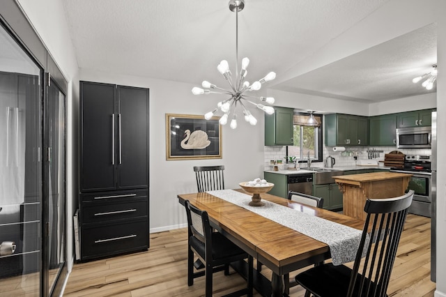 3717 80th Ave N, Brooklyn Park, MN 55443 - dining space with light wood-style flooring, a chandelier, a textured ceiling, and baseboards