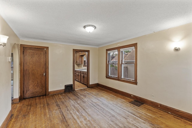 5420 Fremont Ave N, Brooklyn Center, MN 55430 - unfurnished bedroom featuring wood finished floors, a textured ceiling, baseboards, arched walkways, and a sink