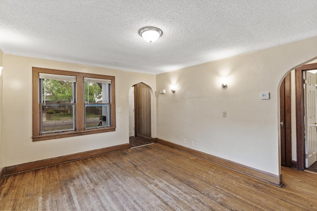 5420 Fremont Ave N, Brooklyn Center, MN 55430 - empty room featuring arched walkways, wood finished floors, baseboards, and a textured ceiling
