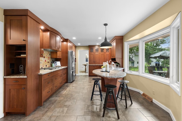 6521 Gleason Rd, Edina, MN 55439 - kitchen featuring a breakfast bar, light stone countertops, brown cabinetry, appliances with stainless steel finishes, and glass insert cabinets