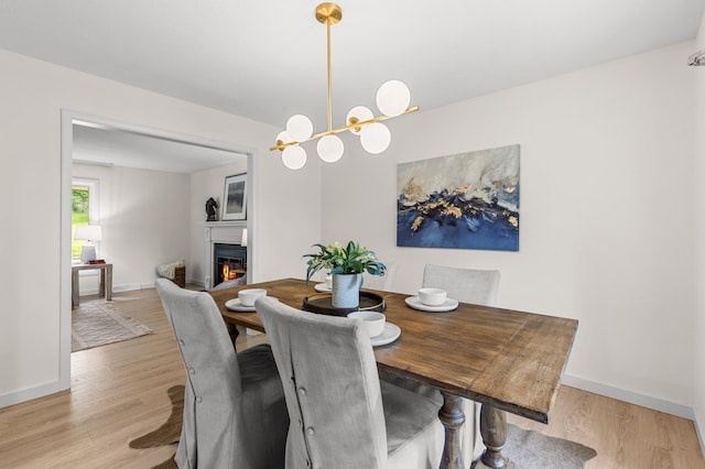 6521 Gleason Rd, Edina, MN 55439 - dining space featuring a glass covered fireplace, light wood finished floors, and a chandelier