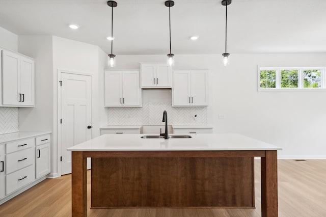 10633 29th St NE, Saint Michael, MN 55376 - kitchen featuring a sink, light wood-style flooring, decorative backsplash, an island with sink, and decorative light fixtures
