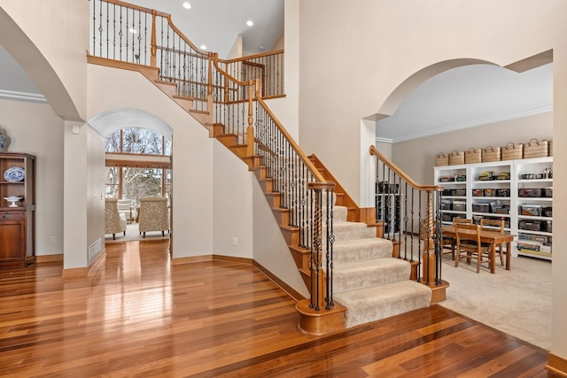 9256 Gateway Ln, Eden Prairie, MN 55347 - staircase featuring a towering ceiling, arched walkways, baseboards, wood finished floors, and recessed lighting