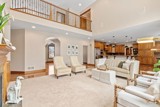 9256 Gateway Ln, Eden Prairie, MN 55347 - living area featuring a towering ceiling, arched walkways, wood finished floors, recessed lighting, and a fireplace with raised hearth