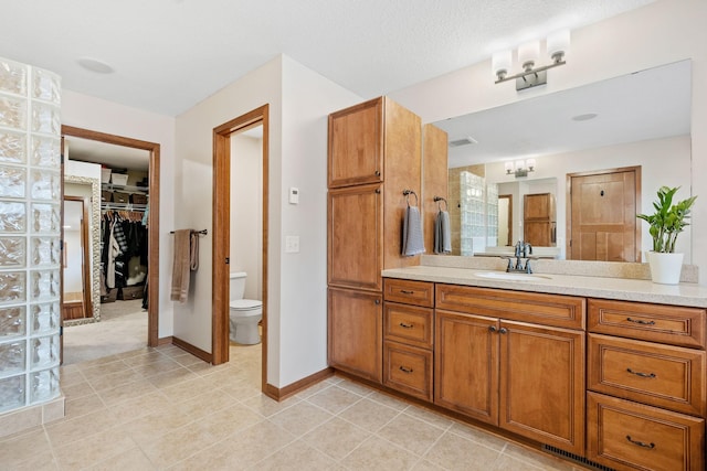 9256 Gateway Ln, Eden Prairie, MN 55347 - bathroom featuring toilet, vanity, a walk in closet, tile patterned flooring, and baseboards