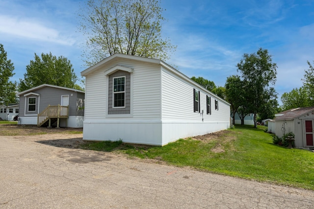 215 Mckay Ave # 59, Alexandria, MN 56308 - view of home's exterior featuring a lawn and an outdoor structure