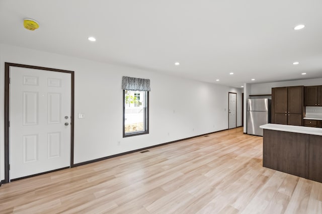 215 Mckay Ave # 59, Alexandria, MN 56308 - kitchen with freestanding refrigerator, dark brown cabinetry, light wood finished floors, recessed lighting, and light countertops
