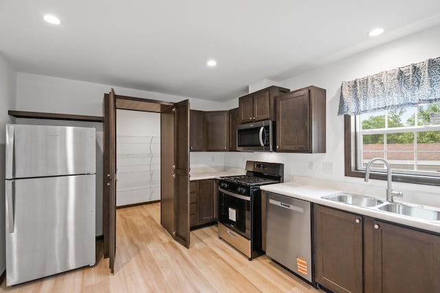 215 Mckay Ave # 59, Alexandria, MN 56308 - kitchen with stainless steel appliances, a sink, dark brown cabinets, light wood-style floors, and light countertops