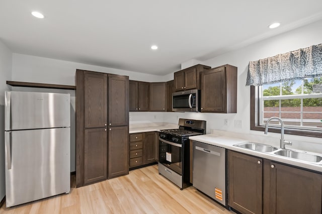 215 Mckay Ave # 59, Alexandria, MN 56308 - kitchen with appliances with stainless steel finishes, a sink, dark brown cabinetry, light wood-type flooring, and light countertops