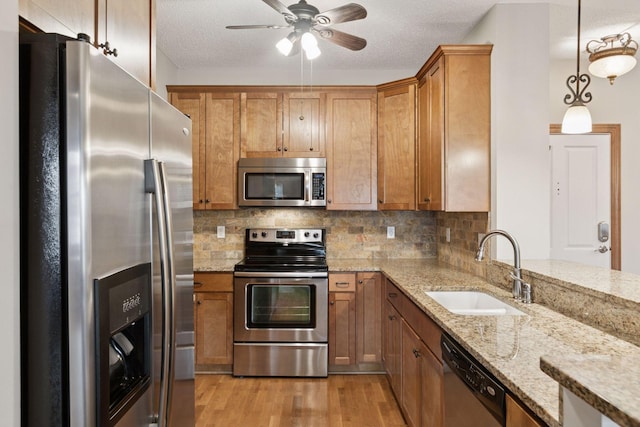 2670 Kelley Pkwy Unit 115, Orono, MN 55356 - kitchen featuring appliances with stainless steel finishes, a sink, brown cabinets, and light wood-style floors