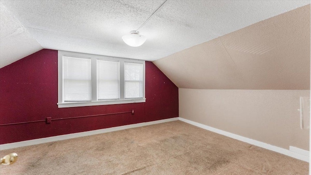1125 9th Ave SE, Saint Cloud, MN 56304 - additional living space featuring vaulted ceiling, carpet, baseboards, and a textured ceiling